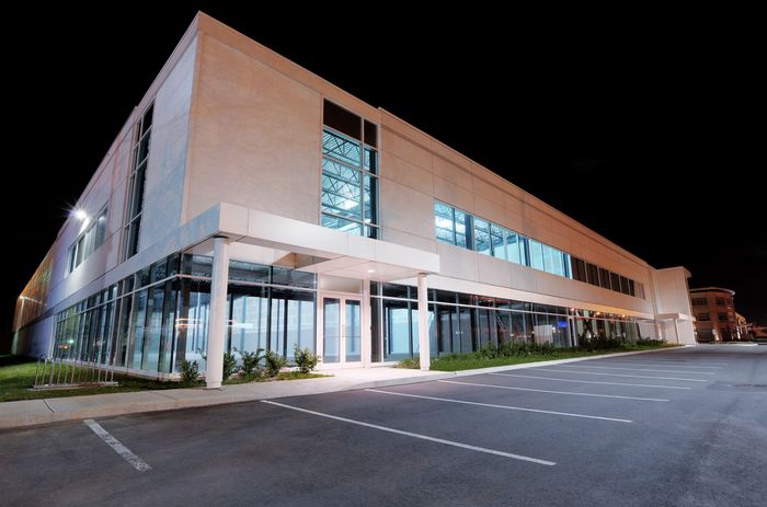 The outside of an empty office building at night, lit from the inside with powerful lighting.